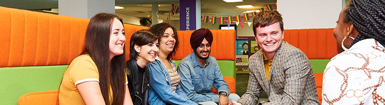 Students in a seating area of the Students Union, smiling and talking between themselves