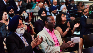 A crowd of seated people applauding towards a stage.
