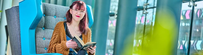 Psychology student sitting in library reading a book