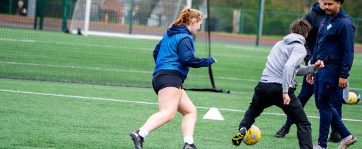 A female student with football going towards a male student