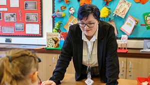 student teacher in classroom lesson with young pupils engaged in activity.